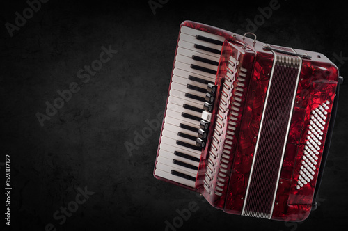 Red accordion on wooden grey background. Write text photo