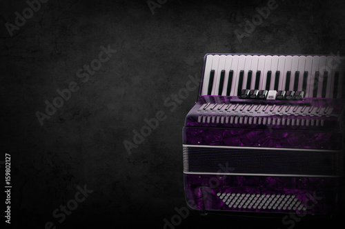 Part pink accordion on wooden grey background. Write text