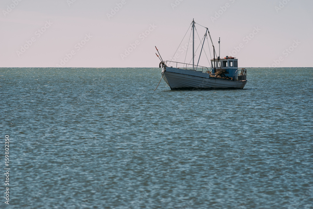 Small fishing ship at anchor in blue water