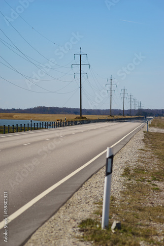 Straight road and high-voltage power transmission line against blue sky