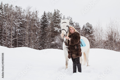 Nice girl and white horse outdoor in a winter