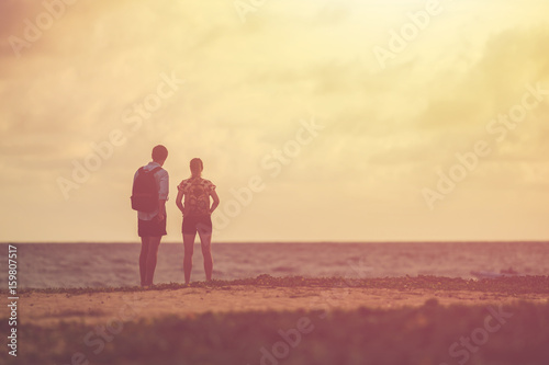 Silhouette of couple people or tourist standing on the beach in sunset time. Warm tone and vintage filter effect