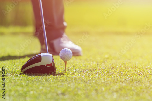 A man playing golf in green course. Focus on golf ball.