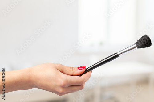 female hand holding a professional makeup brush