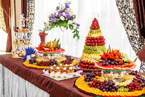 Elegant table with fruit and cakes. The concept of a party, food and wedding.