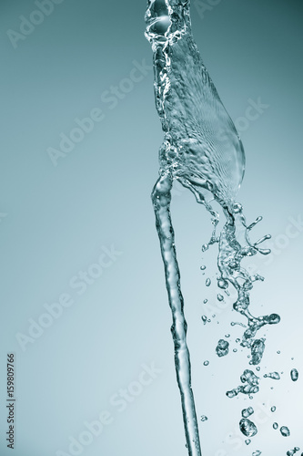 A stream of filtered natural water on a blue background. Splash of mineral drinking water