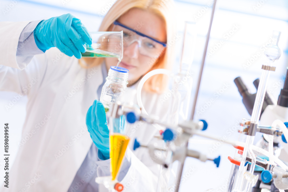 Female laboratory assistant with chemical experiment in scientific laboratory