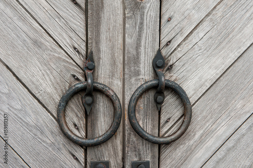 Fototapeta Naklejka Na Ścianę i Meble -  Vintage dark wooden gates with round metal handles in the form of rings. Background.