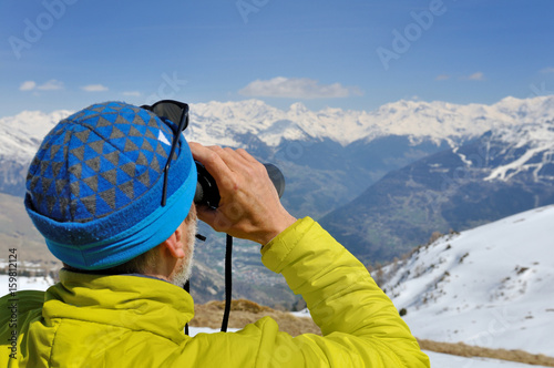 homme observant la montagne aux jumelles