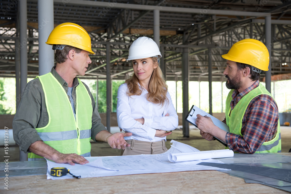 mature builders and contractor talking during work on construction site mature builders and contractor talking during work on construction site