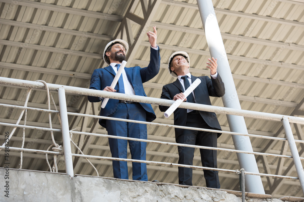 middle aged architects in formal wear talking on construction site