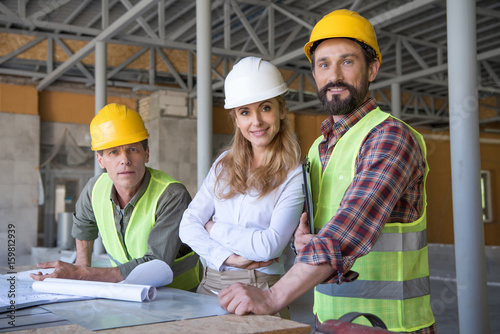 middle aged constructors and contractor looking at camera during work on construction site