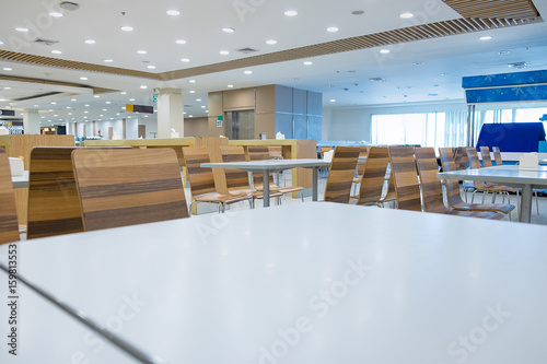 Interior of white table and wooden table on food court in shopping mall.