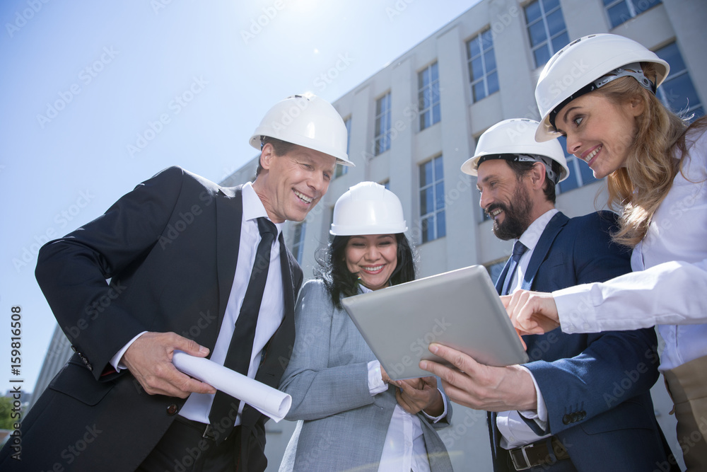 Low angle view of professional team of architects using digital tablet while working together