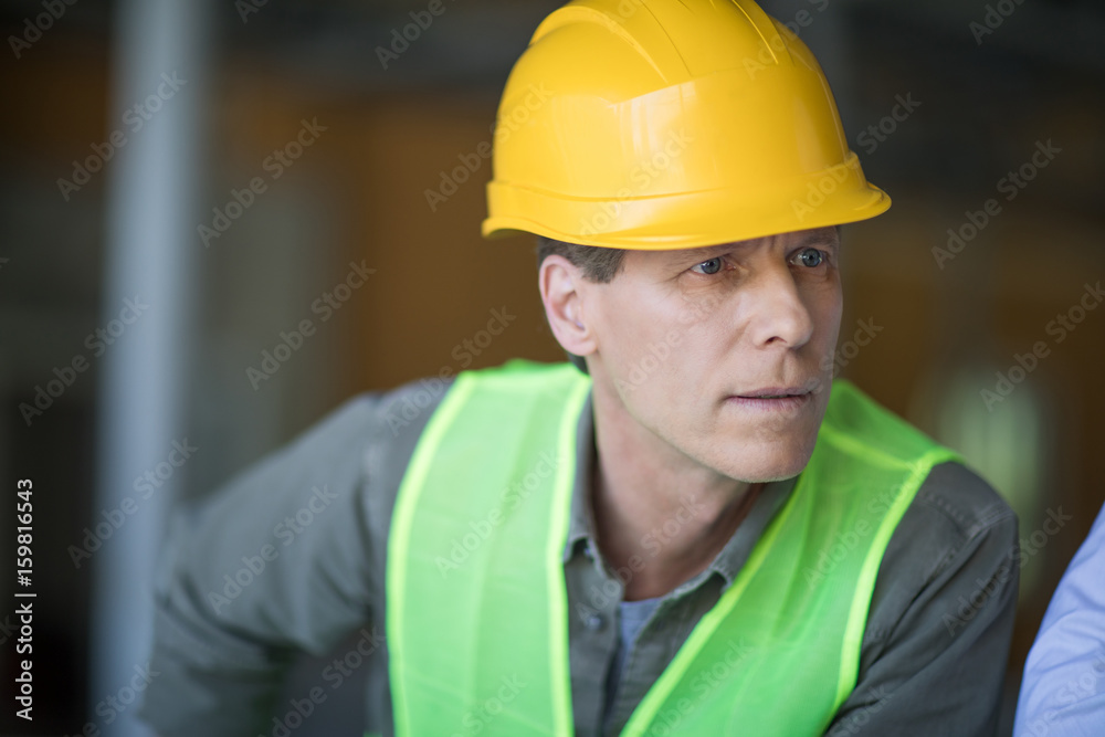 Close-up portrait of professional middle aged engineer in hard hat looking away Close-up portrait of professional middle aged engineer in hard hat looking away