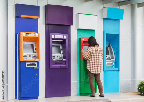 asian woman standing withdrawing money from banking machine or ATM(Automatic Teller Machine)     photo