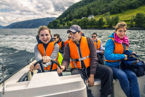 Portrait of young and attractive people, friends in the motorboat driving somewhere on a picnic. Happy faces, having fun, Norway.