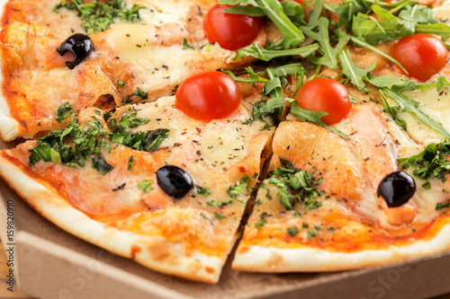 Italian pizza with salmon, cherry tomatoes, arugula and cheese