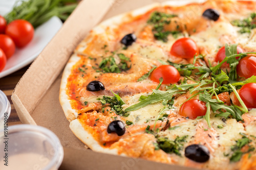 Thin crust italian pizza with salmon in cardboard