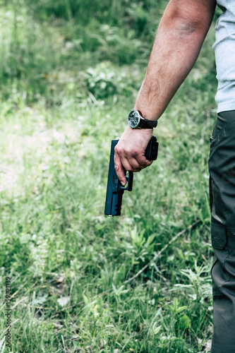 The gun is in his hand. The man is ready to shoot at the target