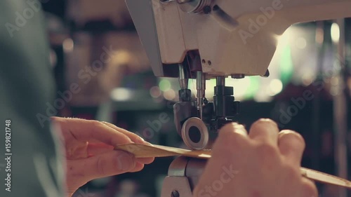 The master makes shoes in the workshop. Using sewing machine to make seam