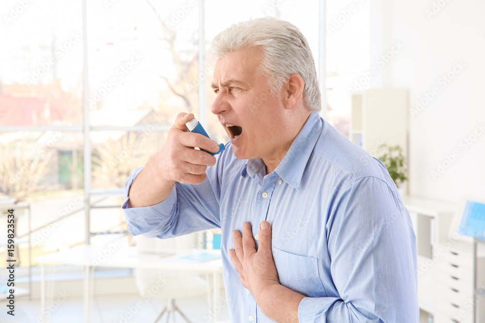 Elderly man using inhaler in clinic