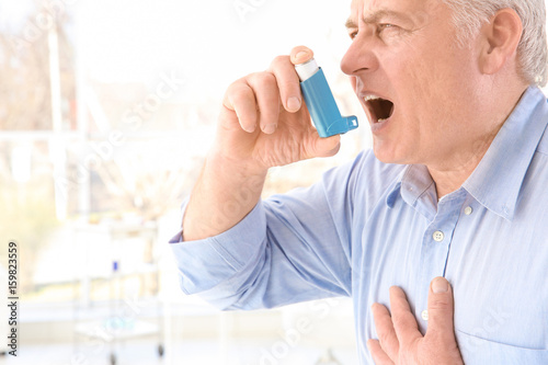 Elderly man using inhaler i...