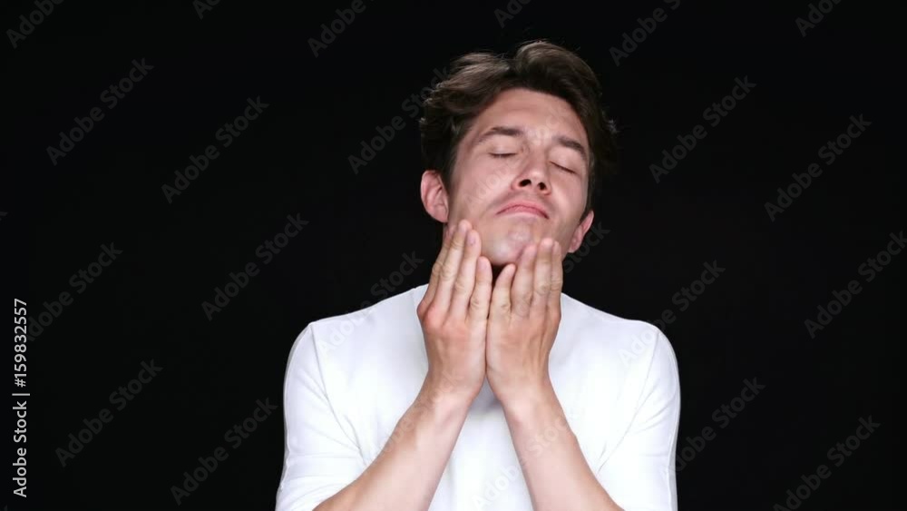 Serious brunette man cleaning up in front of the camera and smiling isolated over black Serious brunette man cleaning up in front of the camera and smiling isolated over black