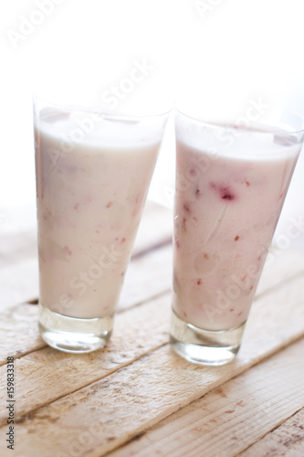 Milk shake yogurt with strawberry slices on a wooden background.