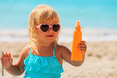 sun protection - little girl with suncream at beach