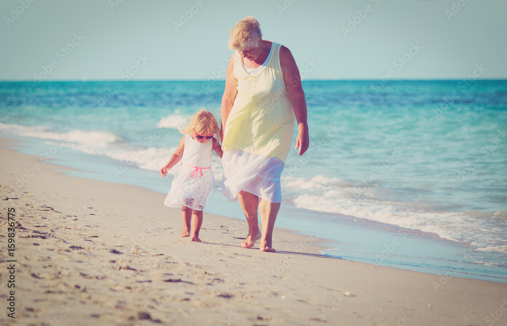 granmother with little granddaughter walk on beach