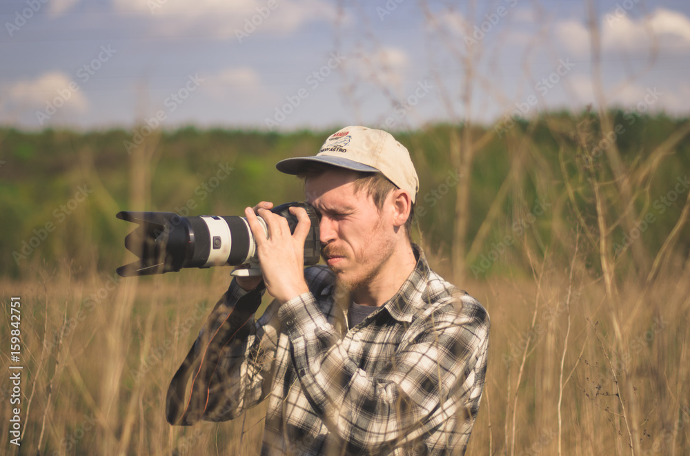 A hipster photographer takes photos in the countryside