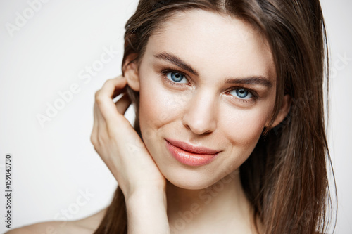 Naked young beautiful girl with natural make up smiling looking at camera over white background. Cosmetology and spa. Facial treatment.