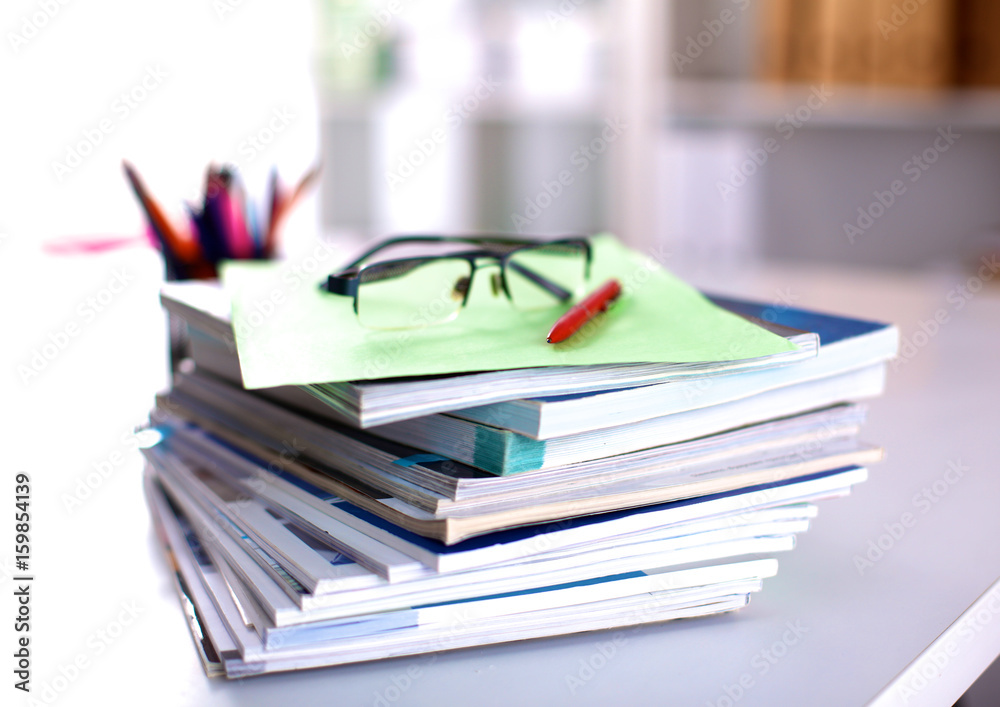 A stack of documentation is on the desktop in the office A stack of documentation is on the desktop in the office