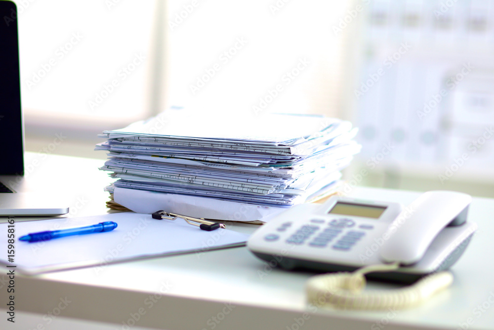 Laptop with stack of folders on table on white background Laptop with stack of folders on table on white background
