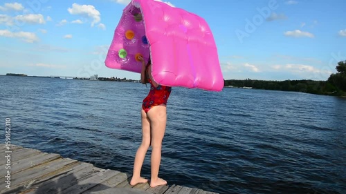 Girl jump on an inflatable mattress in the water