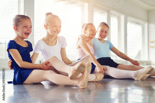 Smiling girls having fun on floor of ballet class