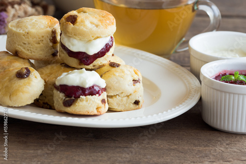 Homemade raisin scones served with homemade strawberries jam,clotted cream and tea.Scones is English pastry for afternoon tea,cream tea. Delicious scones Devon shire or Cornish cream style. 