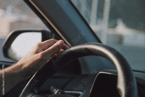 Young man hand holding the car steering wheel
