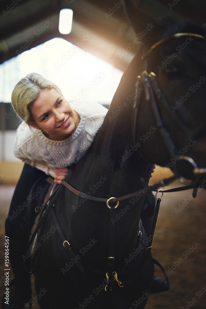Smiling blonde female sitting astride black horse
