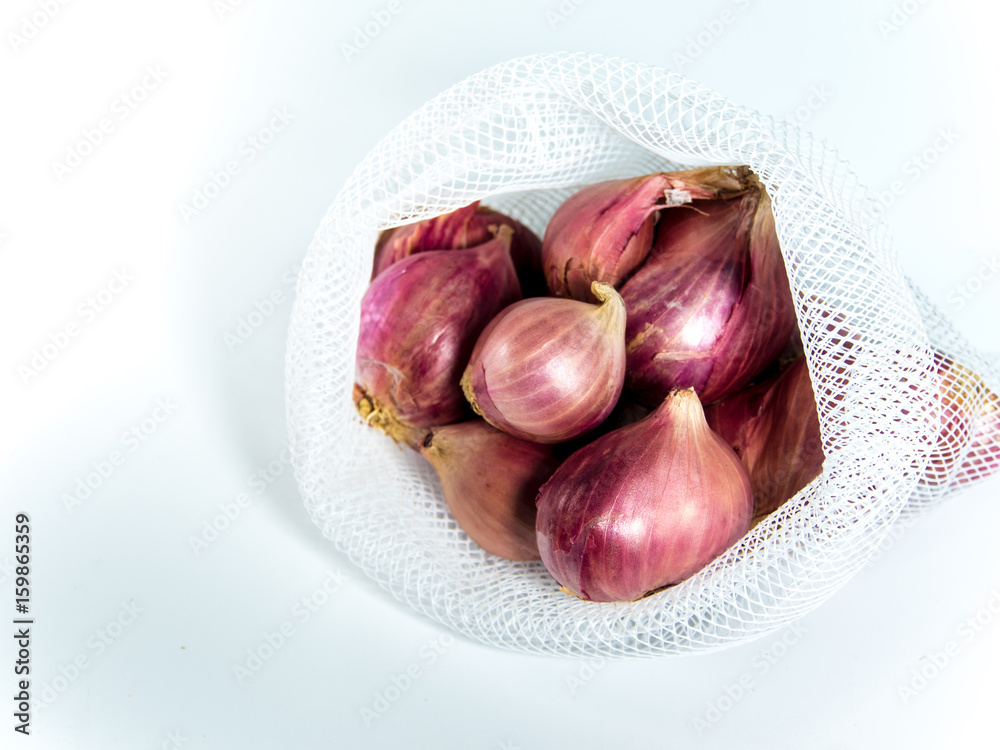 Obraz premium Red onions in mesh bag isolated on white background