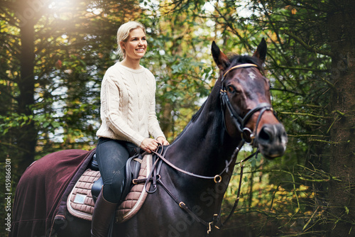 Smiling woman riding a horse in park