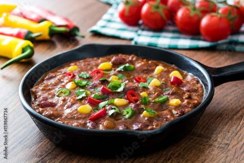 Traditional mexican tex mex chili con carne in a frying pan on wooden table 