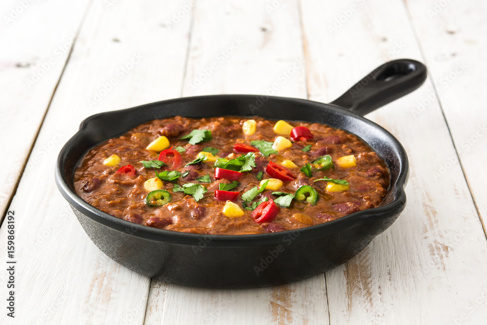Traditional mexican tex mex chili con carne in a frying pan on white wooden table
