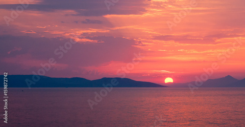 Panoramic image of sunset over the sea with lilac and pink hues in the cloudy sky  