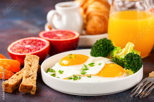 Breakfast - fried eggs with broccoli, muesli, croissant and juice on a table. Selective focus. Copy space