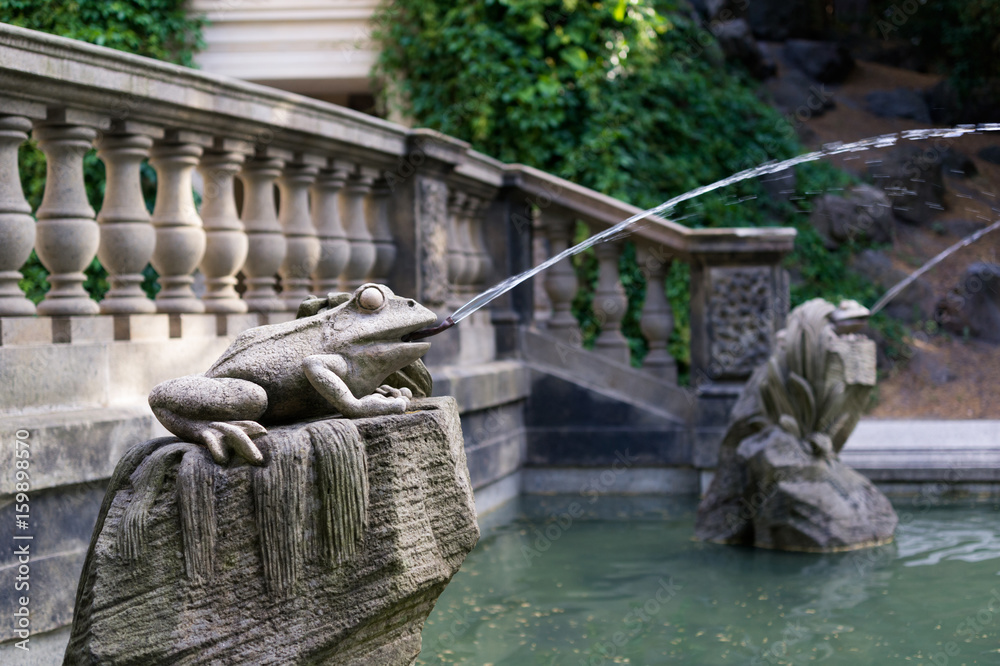 Gargoyle - statue of frog with splashing water from mouth. Animal made of stone as decoration and ornament. Detail of Grotta, fountain from 19th century in Havlicek gardens, Prague
