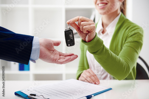 Car rent or sale. Rental agent giving automobile key to customer in the office. 