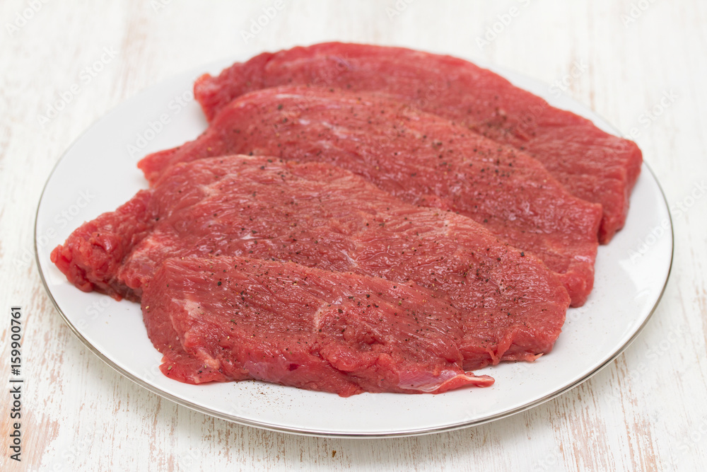 raw meat on white plate on wooden background