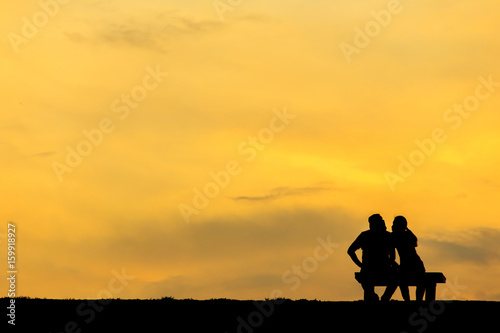 Back view of a couple silhouette sitting on Chair at colorful sunset on background © thechatat